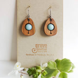 An earring of egg shaped wood frames holding round amazonite beads