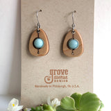 An earring of egg shaped maple wood frames holding round amazonite beads