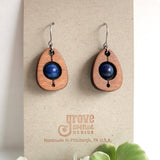 An earring of egg shaped cherry wood frames holding round lapis lazuli beads