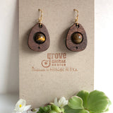 An earring of egg shaped walnut wood frames holding round tigereyei beads